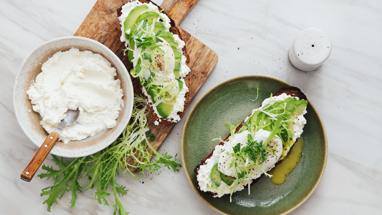 A bowl of ricotta next to bread spread with ricotta