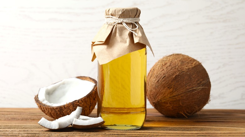 a bottle of liquid coconut oil and coconuts