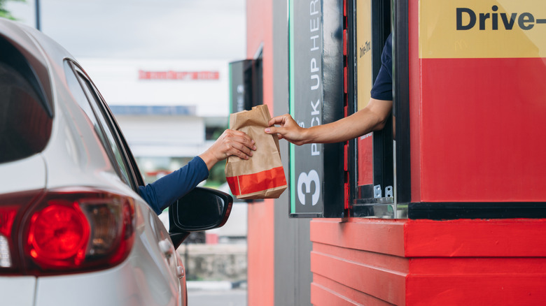 Fast food drive-through with worker handing passenger their food