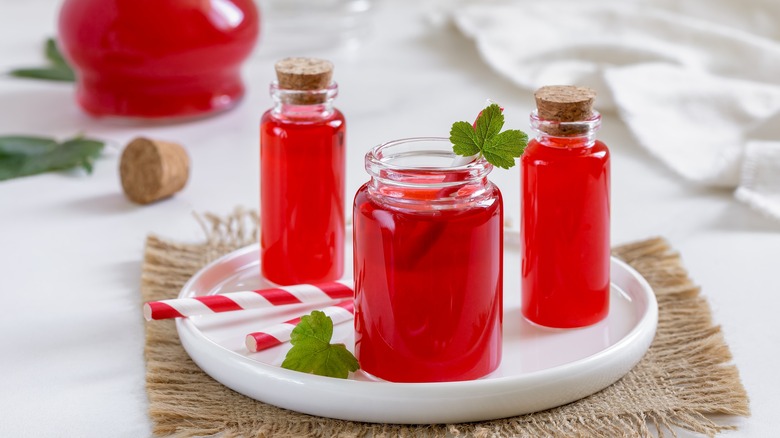 Red syrup in glass bottles with herbs and straws