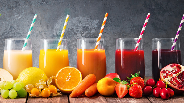Colorful glasses of juice next to their ingredients