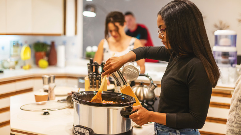 Person stirring slow cooker