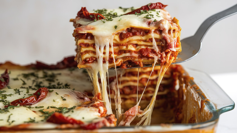 Lasagna being served from a glass lasagna dish