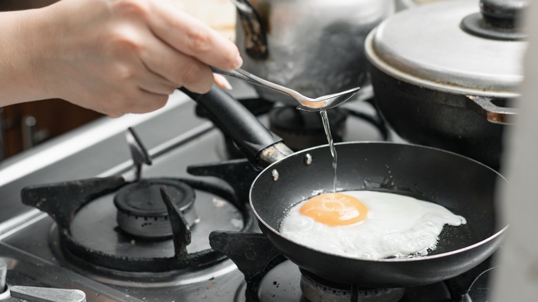 Woman basting egg in oil