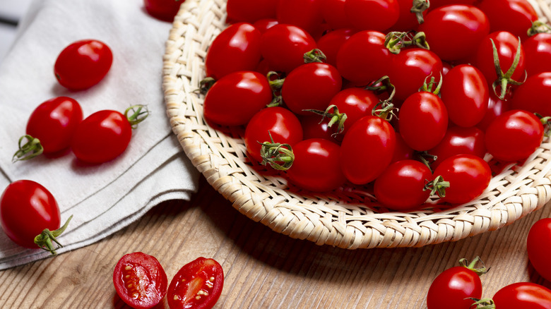 Cherry tomatoes in wicker basket on wood table