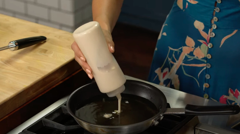 a person making funnel cake at home with a squeeze bottle