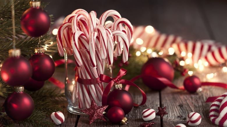 Vase of candy canes surrounded by Christmas decorations