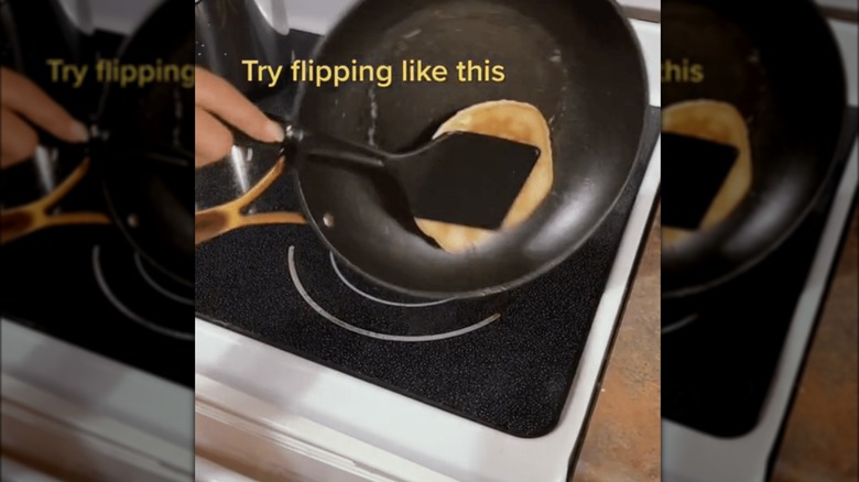 Person flipping a pan with a pancake