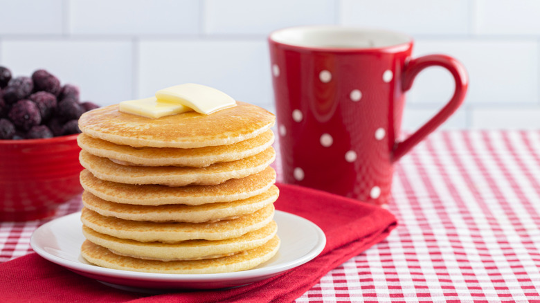 Stack of pancakes in front of polka dot mug