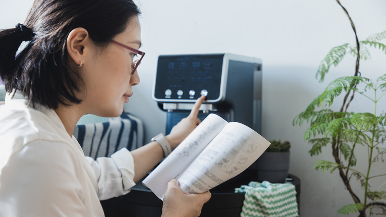 Person reading manual next to an espresso machine