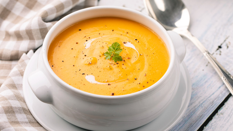 A bowl of carrot puree soup sitting on a table.