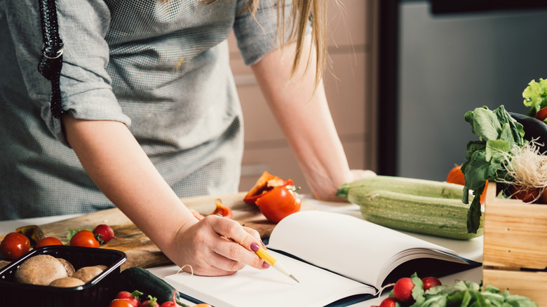 Person reading cookbook on counter