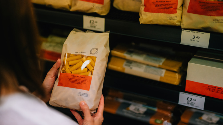 Person reading pasta label at grocery store