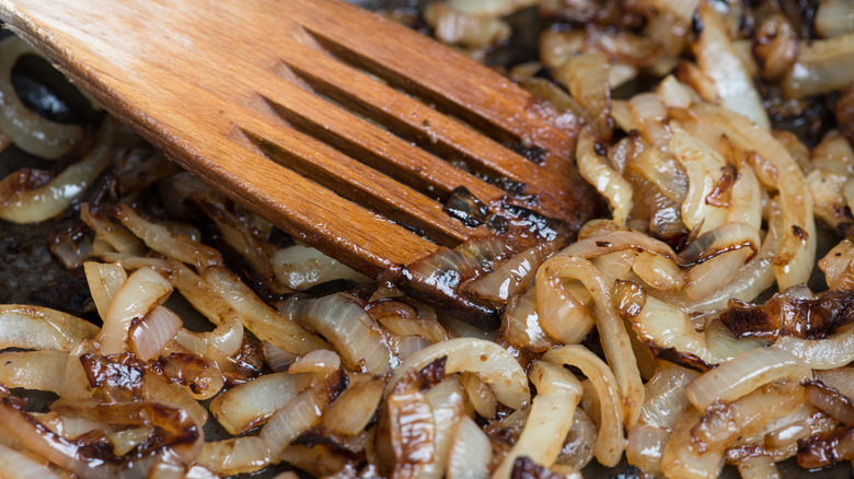Wooden spatula mixing caramelized onions