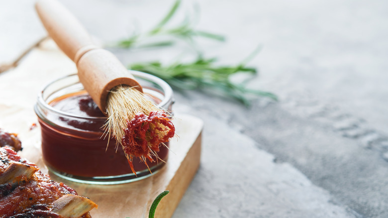 Bowl of barbecue sauce with grill brush resting on top