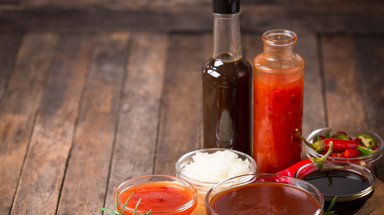 Bottled barbecue sauce on table with ingredients