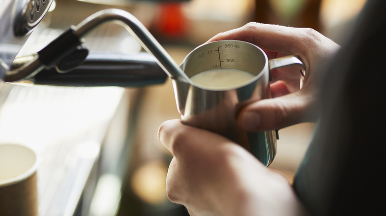 Hands steaming a jug of milk