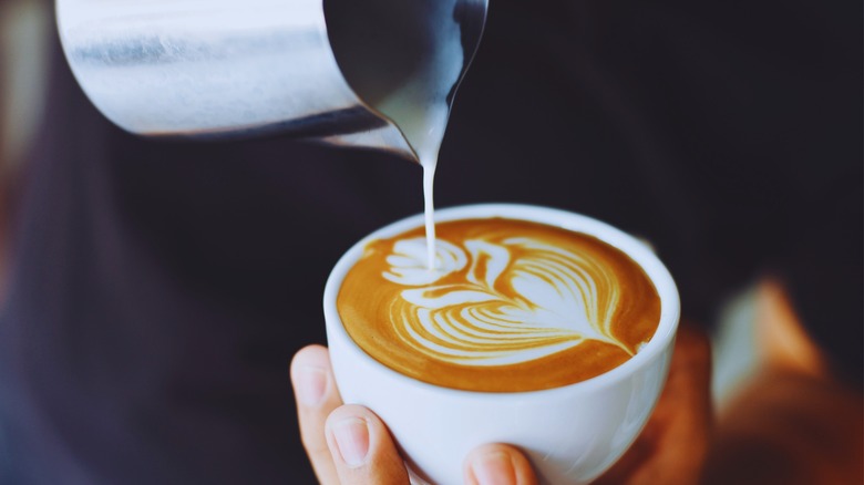  Milk pouring from a pitcher into a latte