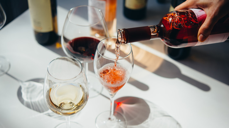 Pouring different varieties of wine into stem glasses