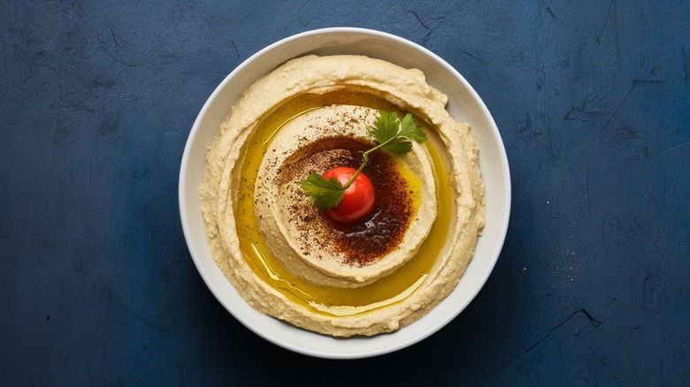 hummus in a white bowl with tomato garnish