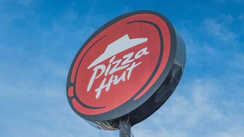 Pizza Hut sign against blue sky with clouds