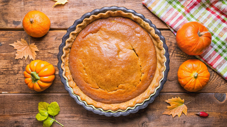 Top down image of pumpkin pie with leaves and pumpkins