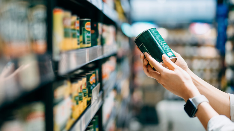 Woman reading back of a can at the supermarket