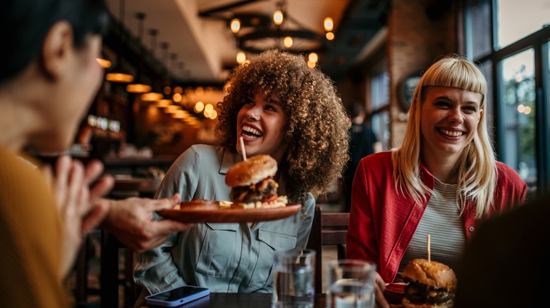 Burger being served to smiling people at restaurant