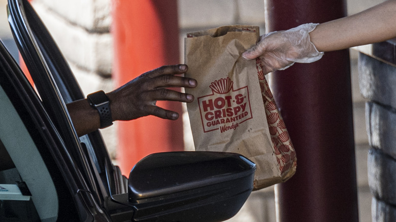 Wendy's employee handing food bag to driver.