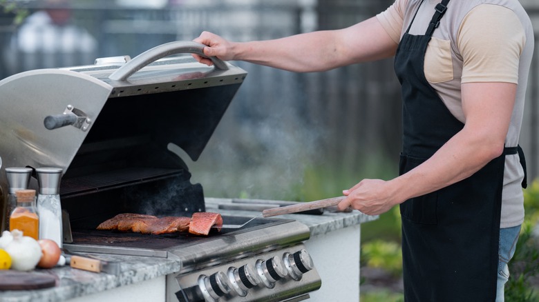 person cooking salmon on gas grill