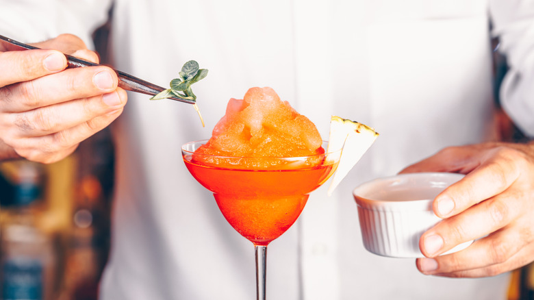 A bartender garnishes a frozen cocktail