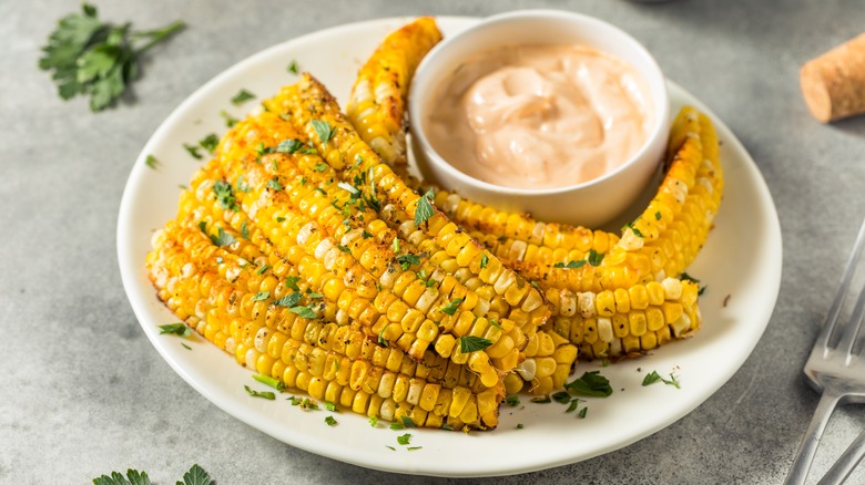 Corn ribs on a white plate with a creamy dipping sauce