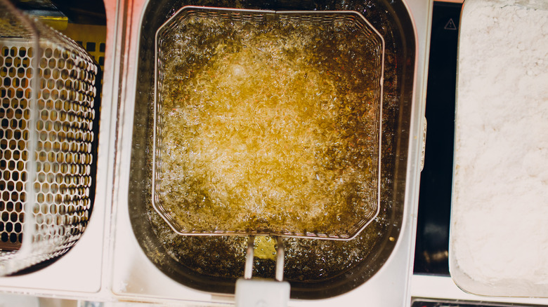 Deep fryer basket submerged in bubbling hot oil