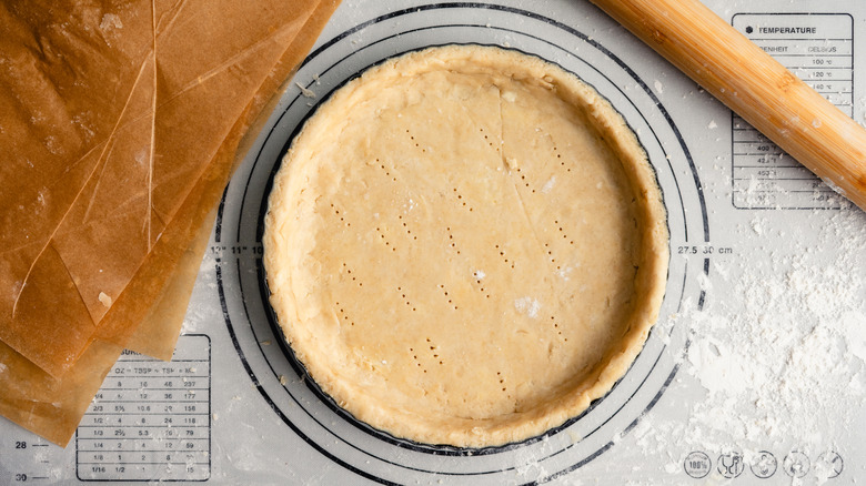 Uncooked pie crust on a pastry mat with a rolling pin