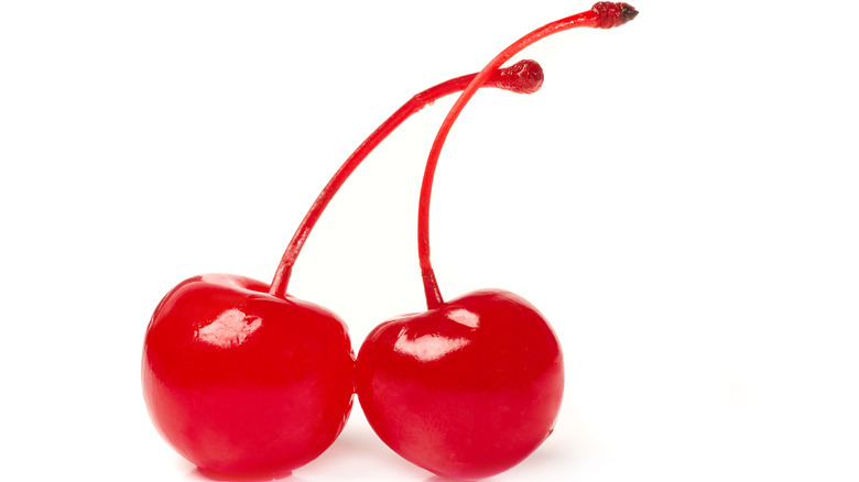 Two maraschino cherries against white background