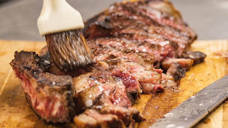 Brushing steak with butter and fat