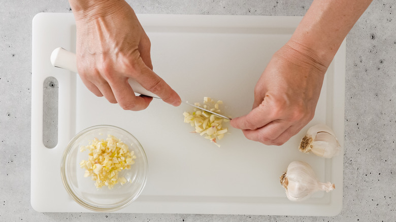 Top-down view of two hands cutting garlic