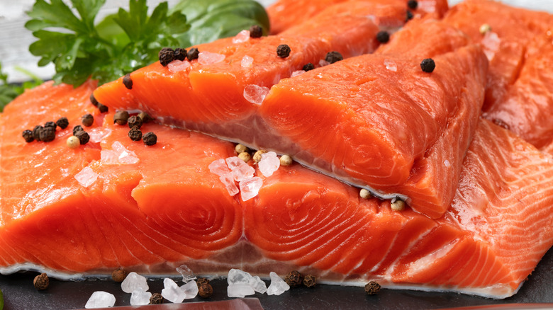 Close up of raw king salmon fillets with black pepper and salt