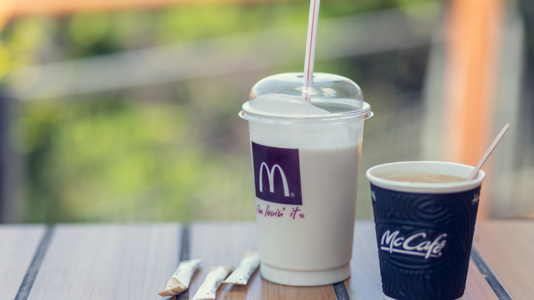 McDonald's vanilla shake sitting next to a McCafe coffee and sugar packets