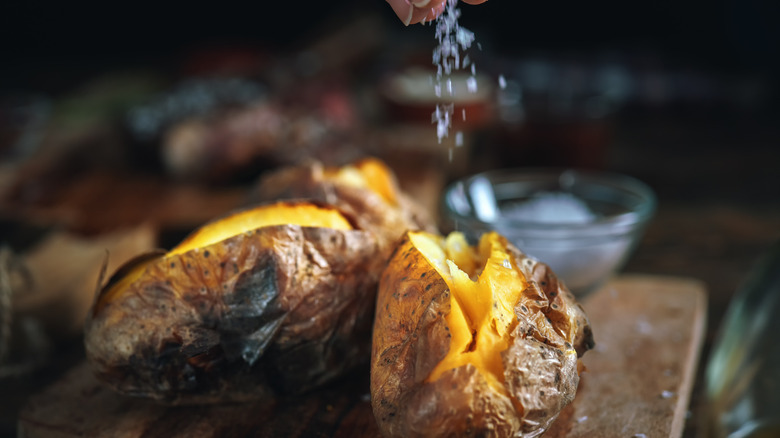 baked potatoes split open with salt