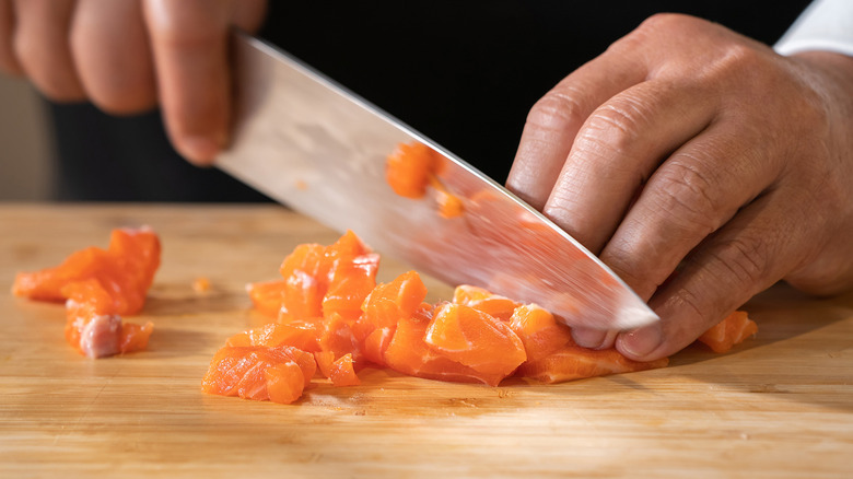 Hand chopping salmon with knife