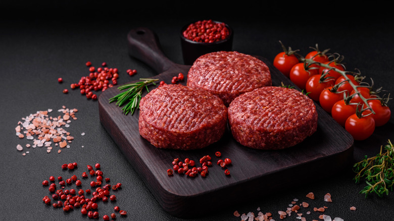 Pre-made burger patties on a cutting board.