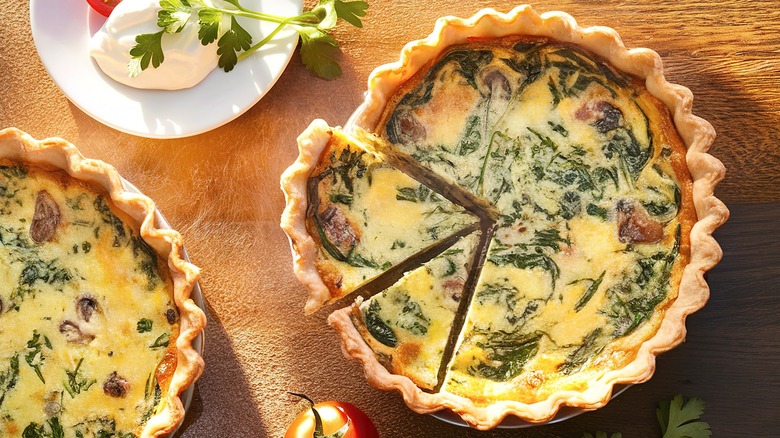 two spinach quiches surrounded by tomatoes and burrata