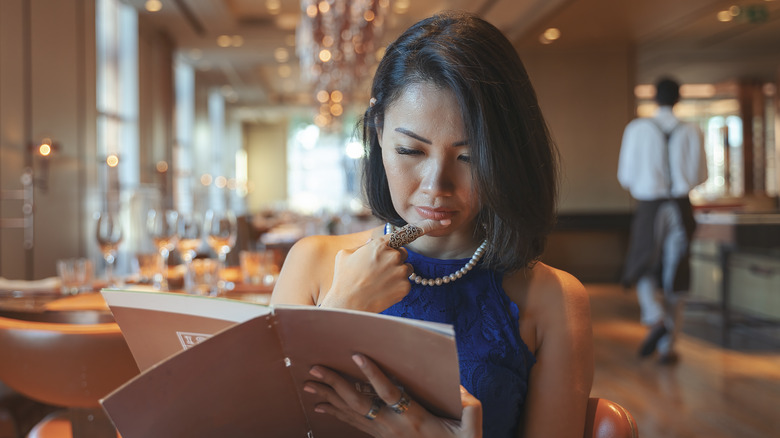 Woman looking at restaurant menu.