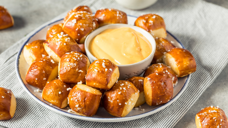 Pretzel bites are on a plate with cheese dip in the middle.