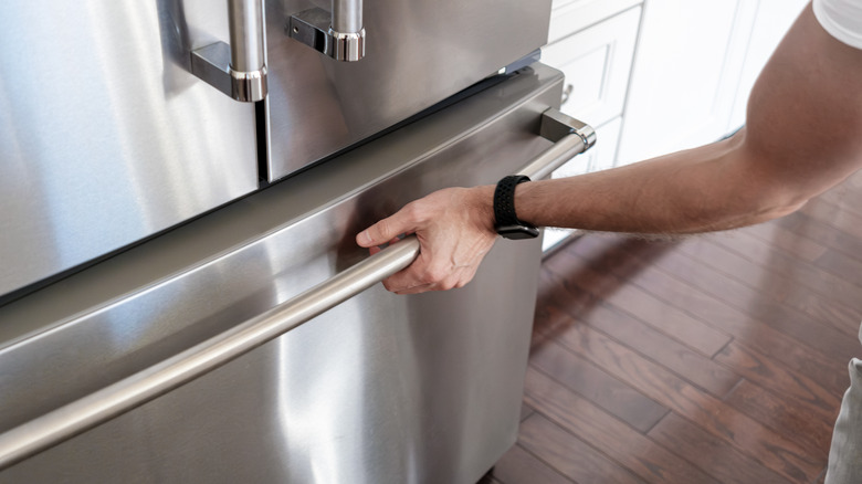 Man's hand opening freezer door