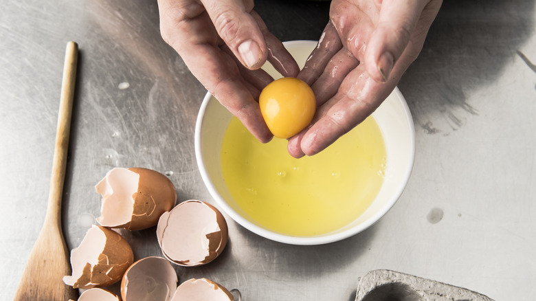 Hands separating egg white and yolk