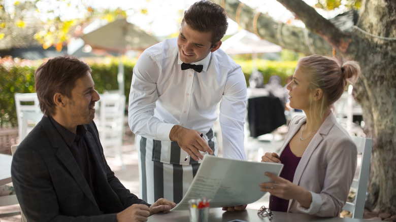 Couple ordering from a waiter at an outdoor restaurant