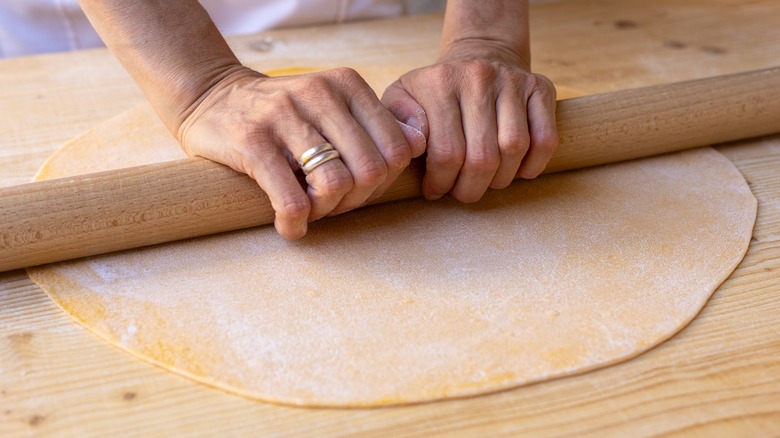 Person stretching pasta rolling pin