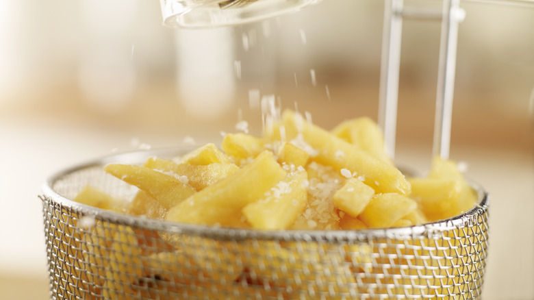 Salting fries in a fryer basket